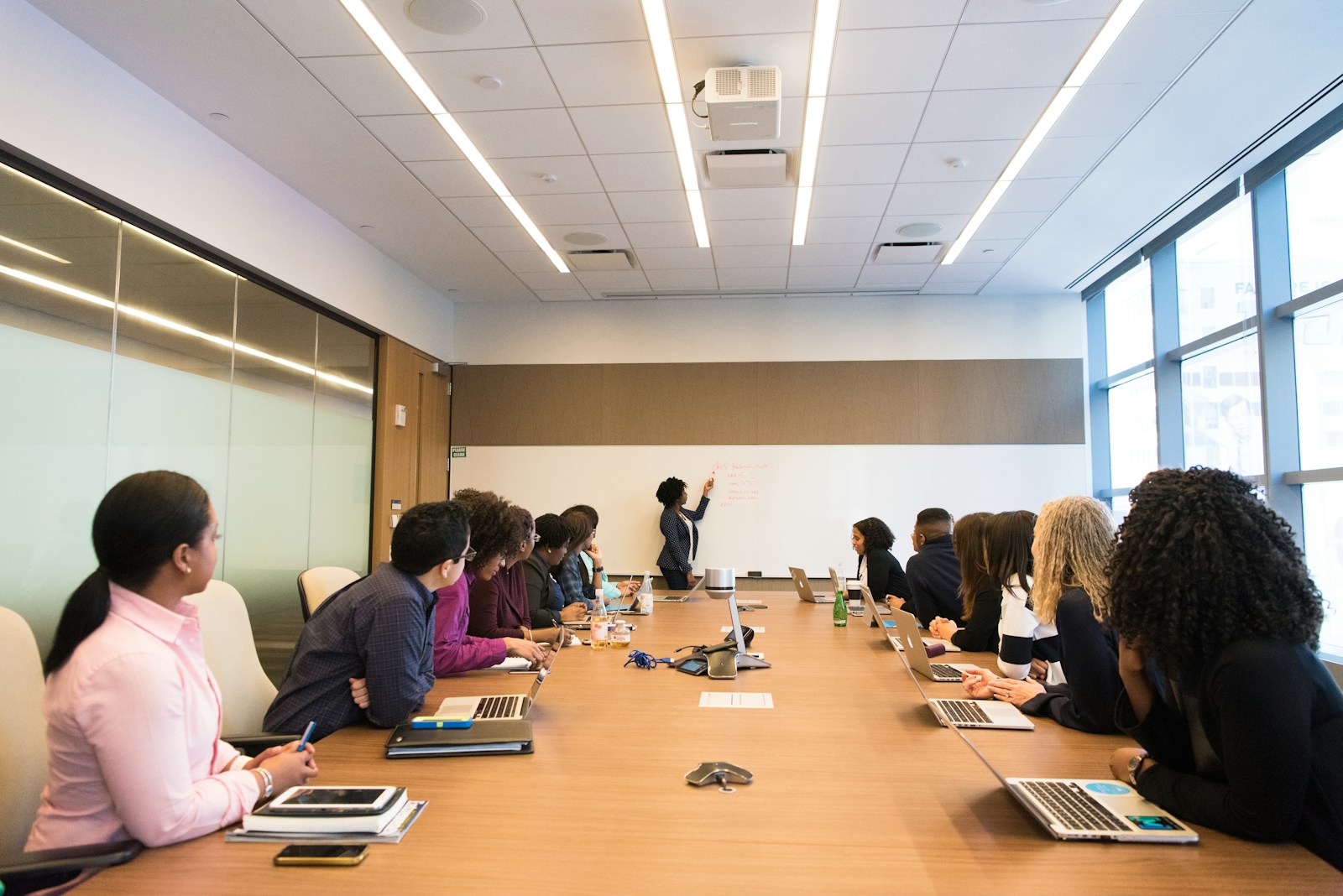 Professionals around a conference table attending a whiteboard presentation